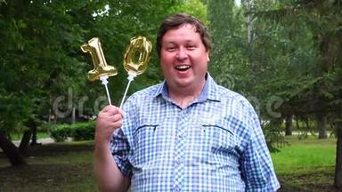 一个大个子拿着两个金色的气球在户外做10个数字。十周年庆典晚会